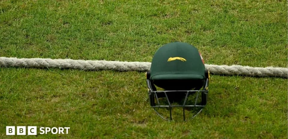 Cricket helmet placed on grass near boundary rope