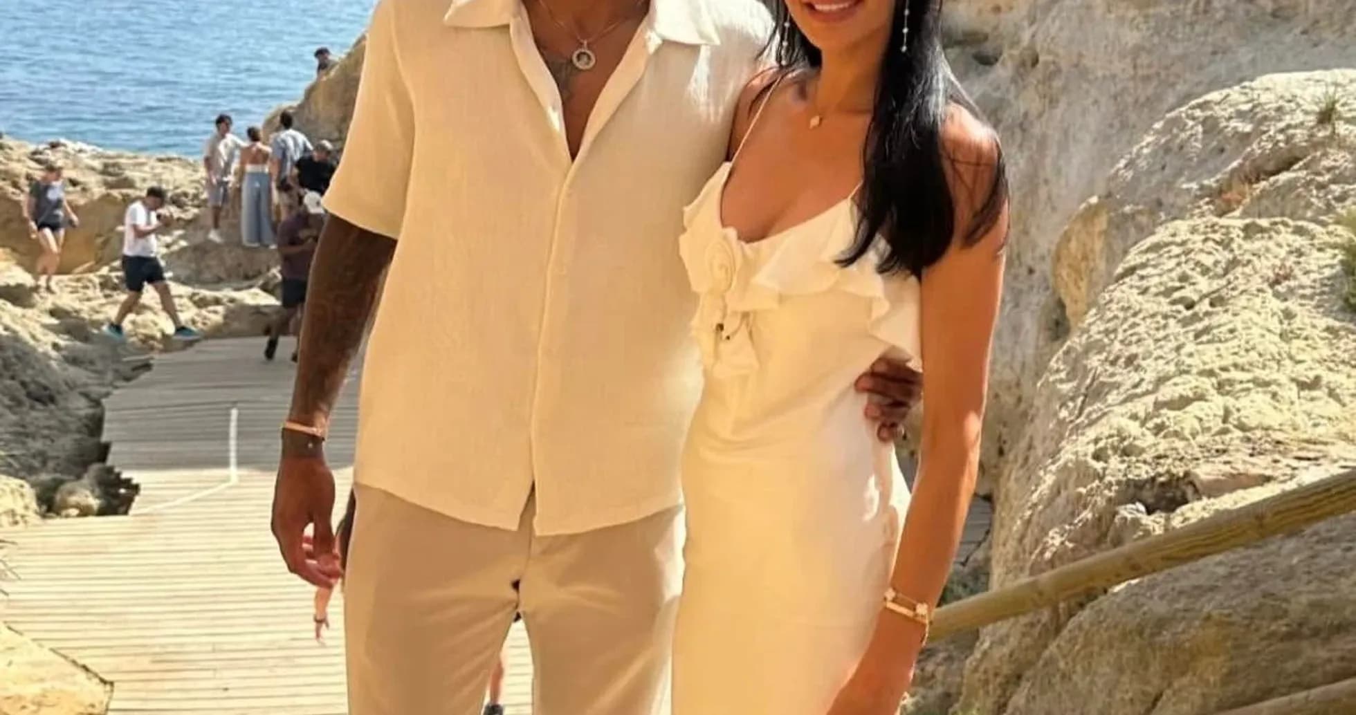 Couple posing on rocky beach with sea backdrop