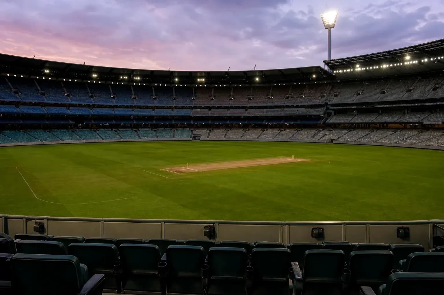 Empty cricket stadium with pitch at dusk
