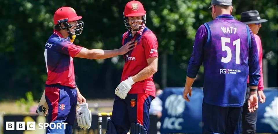Two players in red kits celebrating, one in purple