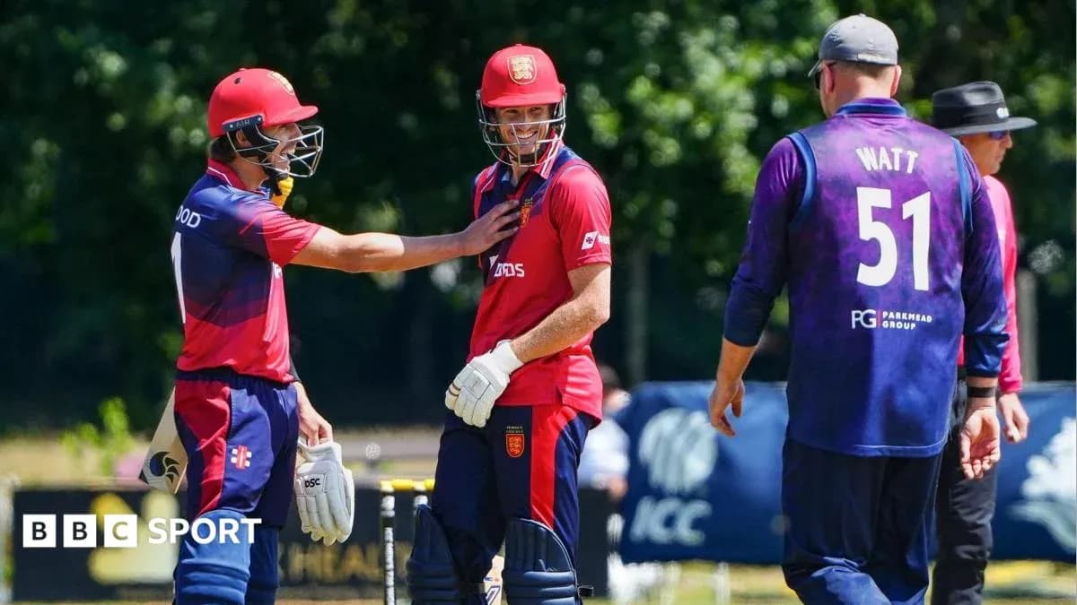 Two players in red kits celebrating, one in purple Two players in red kits celebrating, one in purple
