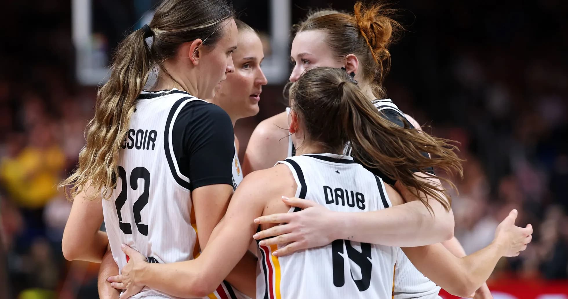 Four basketball players celebrating in team jerseys