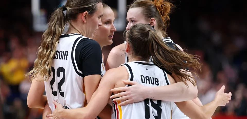 Four basketball players celebrating in team jerseys