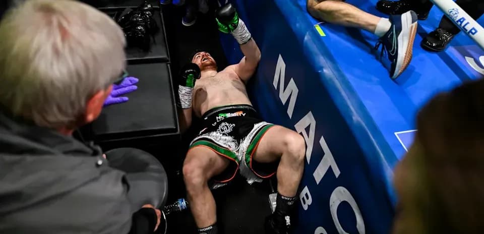 Boxer on the floor after match with corner team