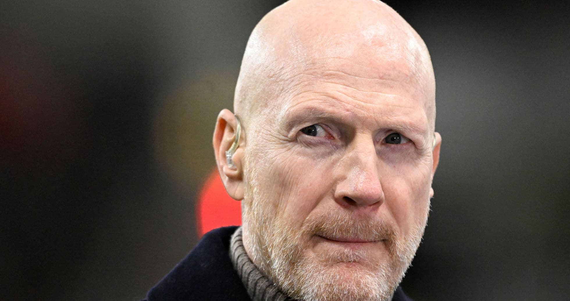 Man with a bald head and beard wearing an earpiece