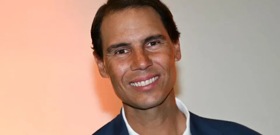 Man smiling in a suit against an orange background