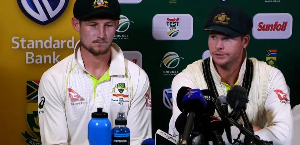 Cricketers at press conference with microphones and water bottles