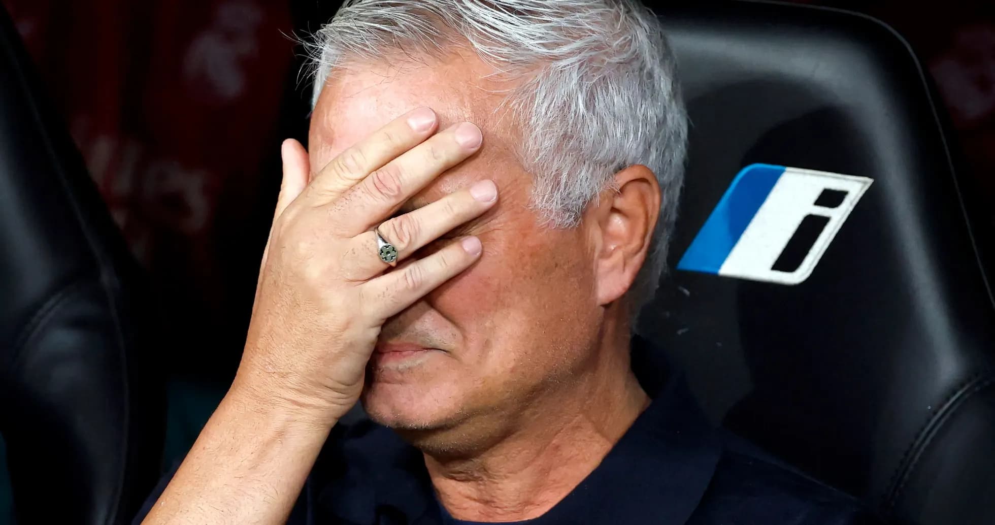Coach sitting on bench with hand on face