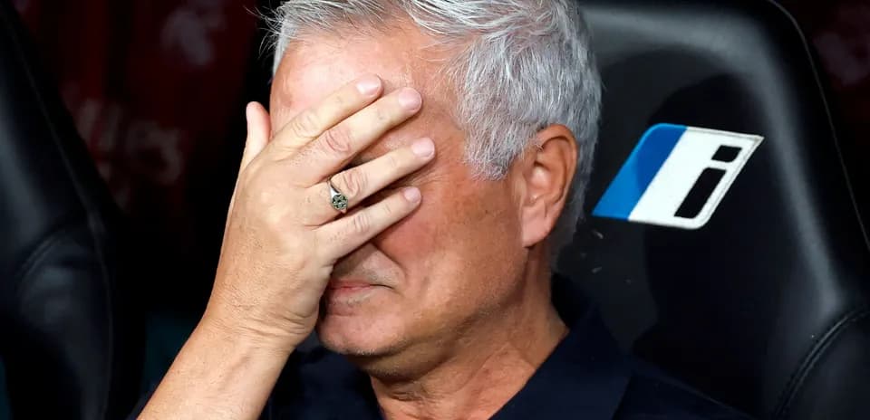 Coach sitting on bench with hand on face