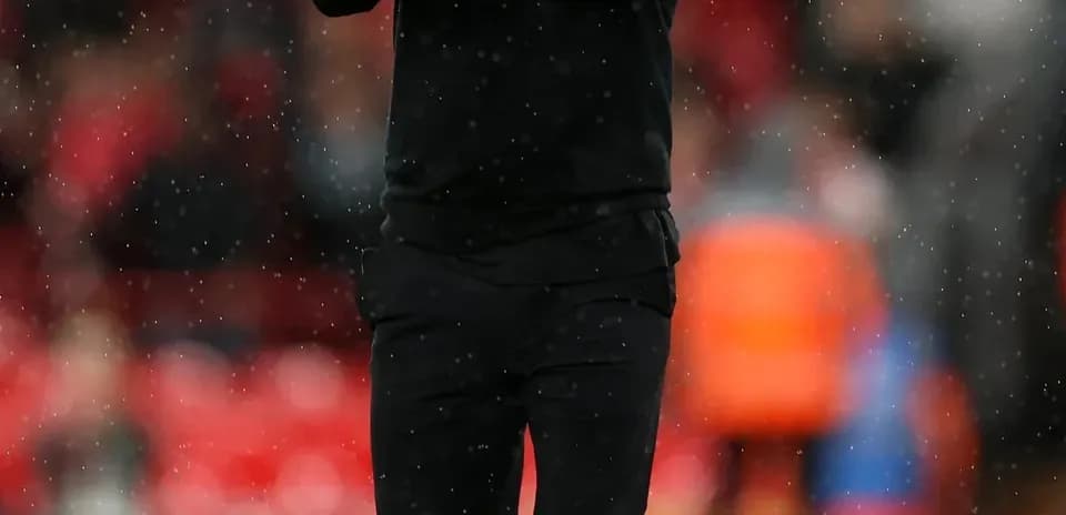 Coach clapping on the pitch during rain