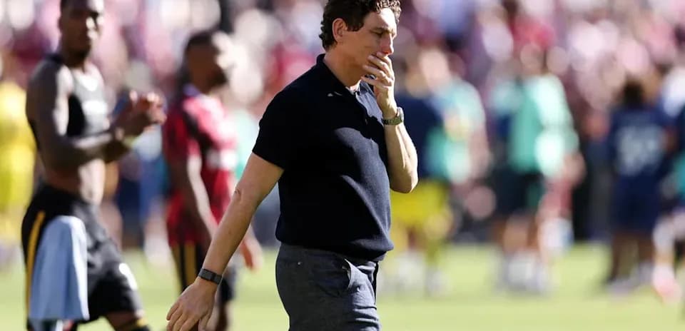 Coach walking on field with players in background