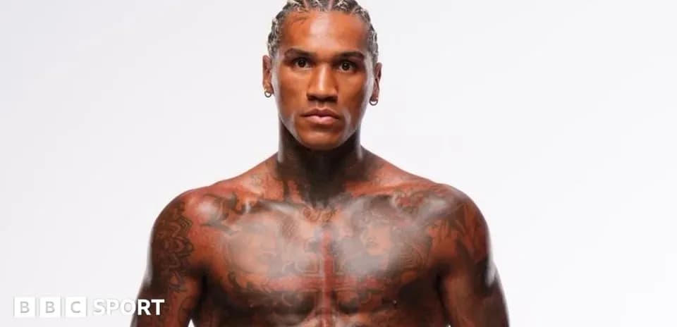 Tattooed athlete posing against a plain background