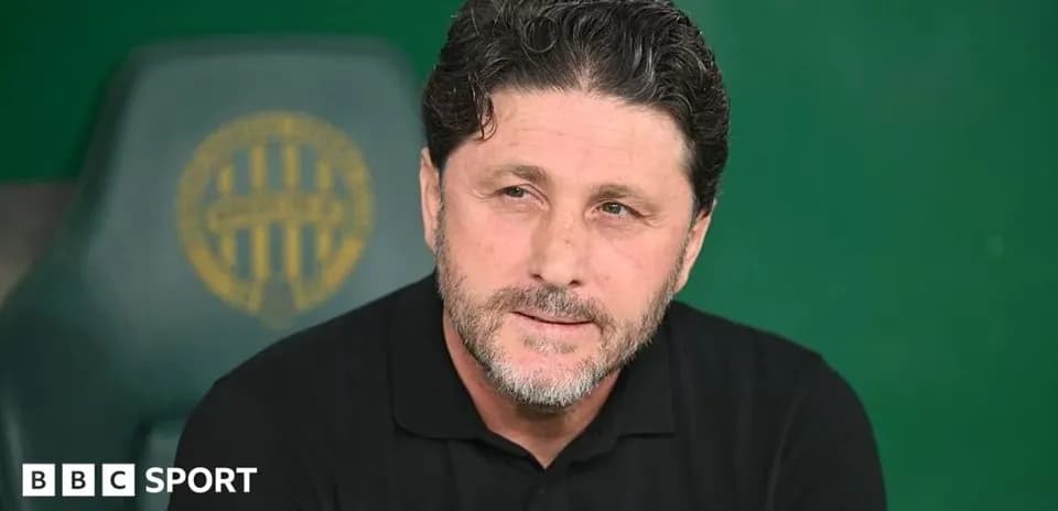 Coach seated on bench during press conference