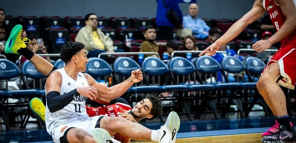 Two basketball players on the court after falling