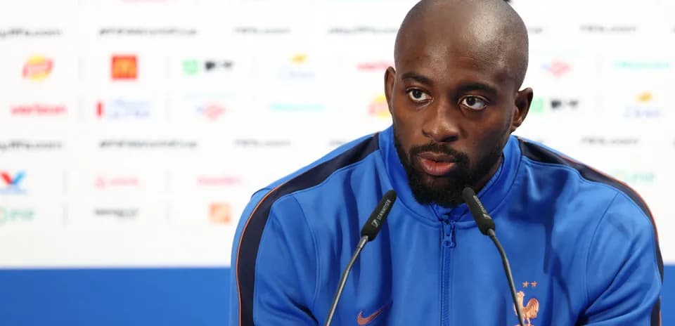 Player speaking at press conference with team logo