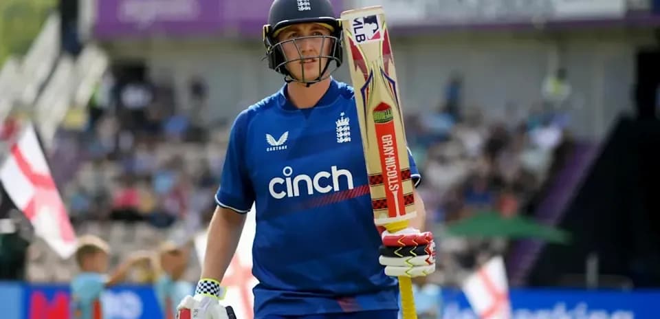 Cricketer walking onto the field with bat
