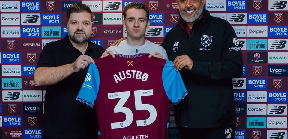 Player holding jersey with team officials at signing event