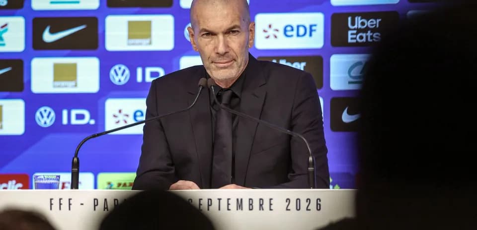 Manager at press conference with sponsor logos in background