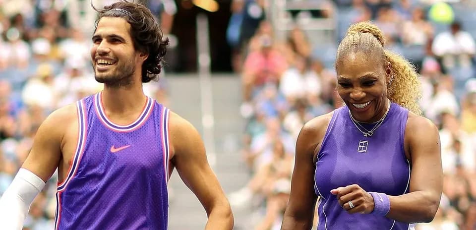 Two tennis players smiling on court during match