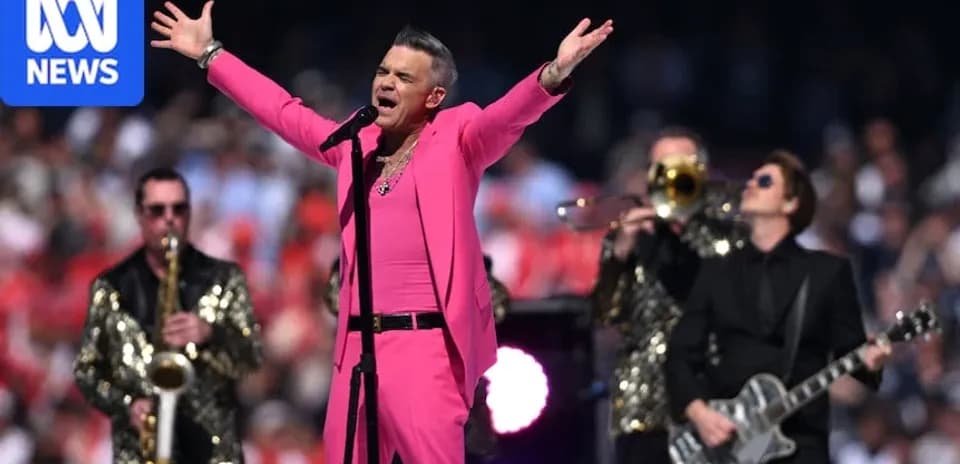 Robbie Williams performing on stage with band