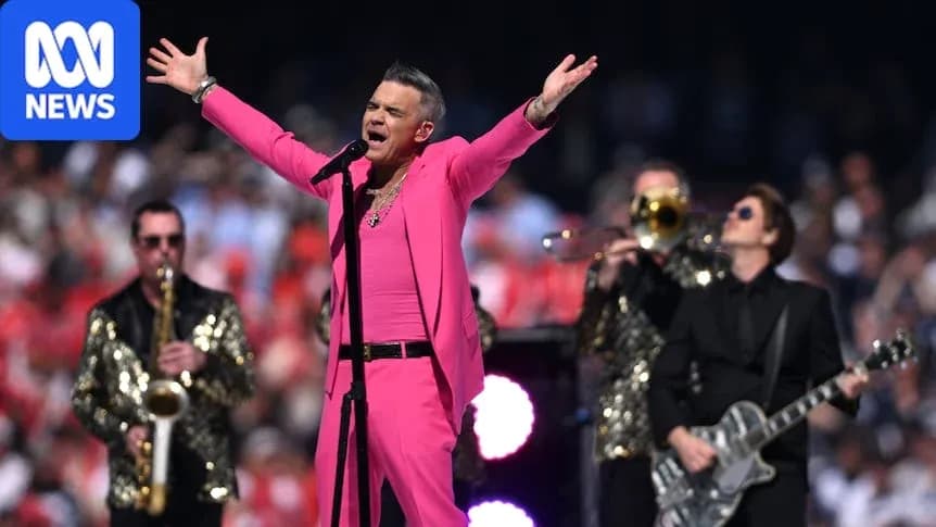 Robbie Williams performing on stage with band