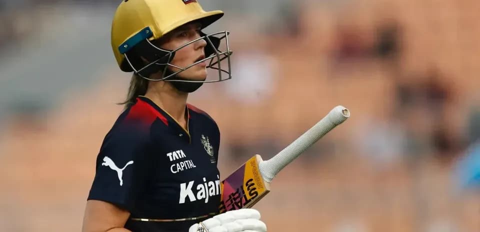 Cricketer in helmet holding bat on field