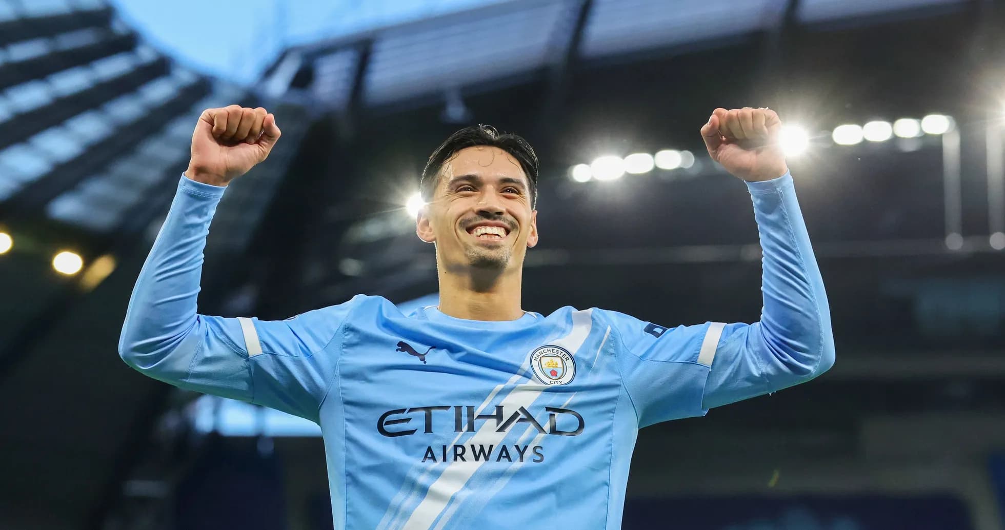 Player celebrating with raised arms in Manchester City kit