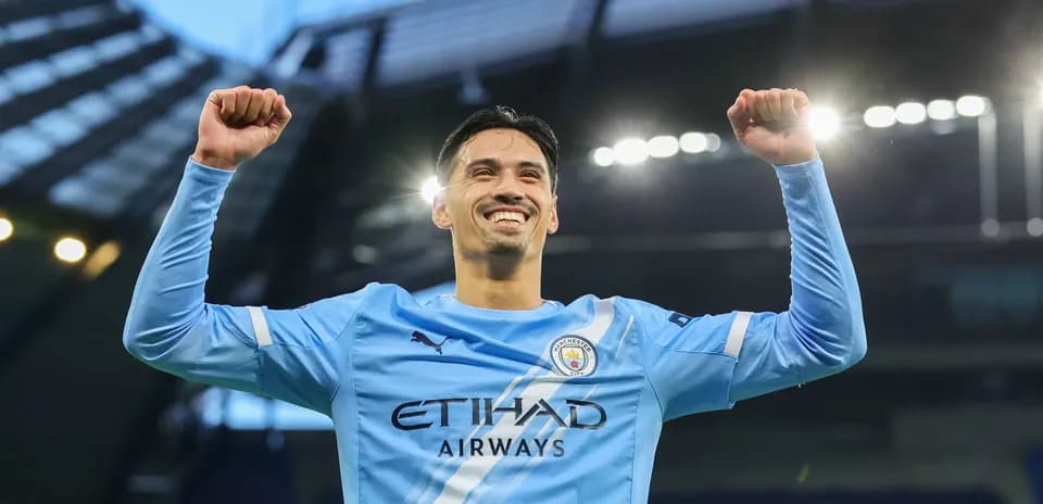 Player celebrating with raised arms in Manchester City kit