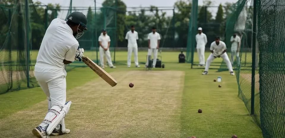 Batsman practicing in cricket nets with teammates