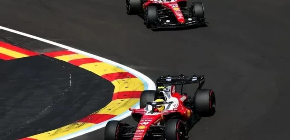 Two Ferrari cars racing on a curved track