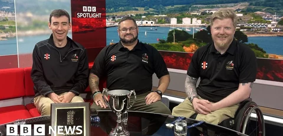 Three men celebrating with a trophy on set