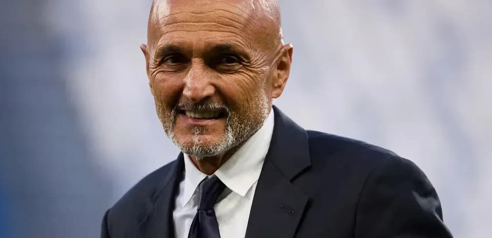 Coach smiling in formal attire at stadium