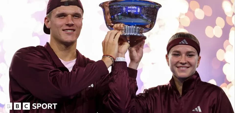 Two athletes celebrating with trophy on podium