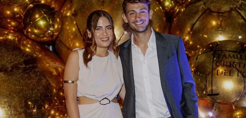 Two individuals posing together at event backdrop