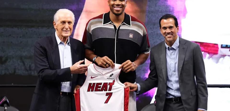 Player holding Miami Heat jersey with team officials