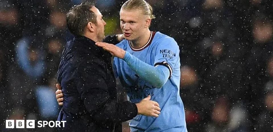 Player and coach embracing in rainy stadium