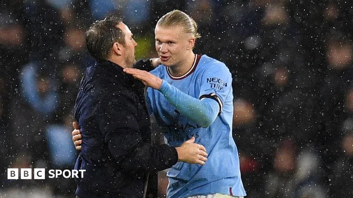 Player and coach embracing in rainy stadium