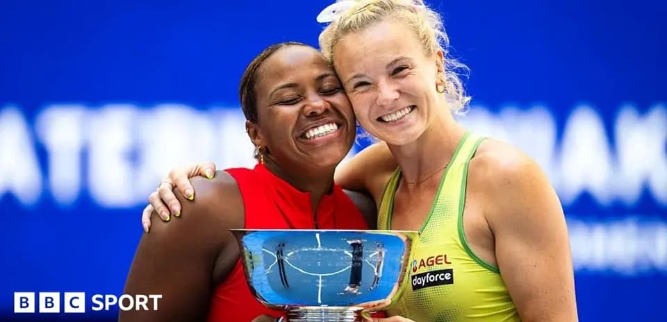 Two tennis players celebrating with a trophy