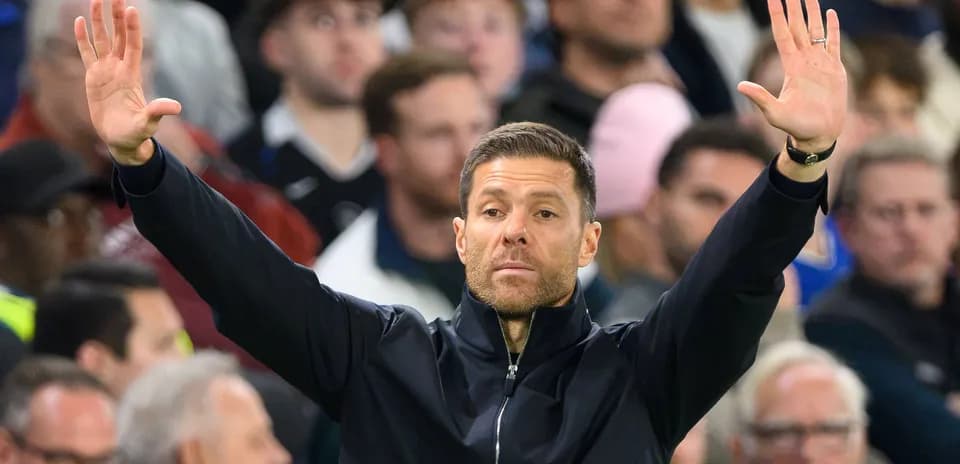 Coach gesturing during a match with fans in background