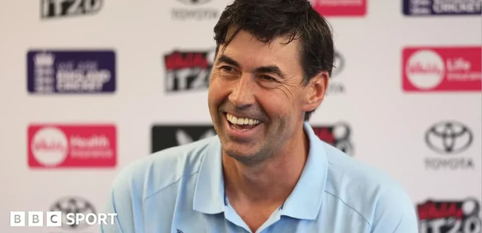 Cricket coach smiling at press conference
