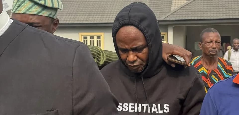 Man in hoodie surrounded by others outside building