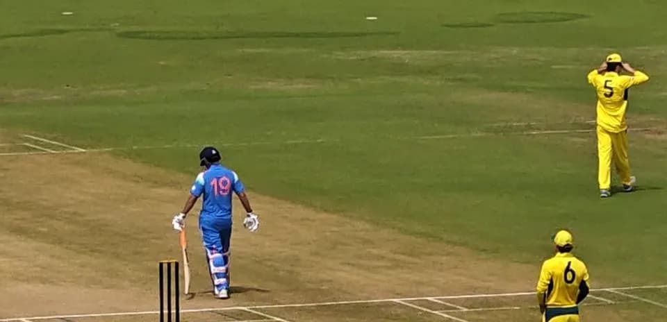 Batsman in blue uniform walking to crease