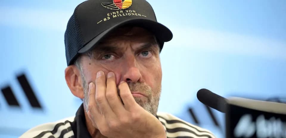Coach at press conference with hand on face