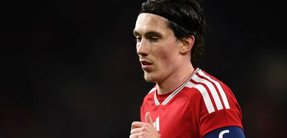 Player in red kit with captain's armband on field