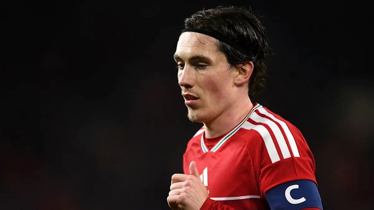Player in red kit with captain's armband on field