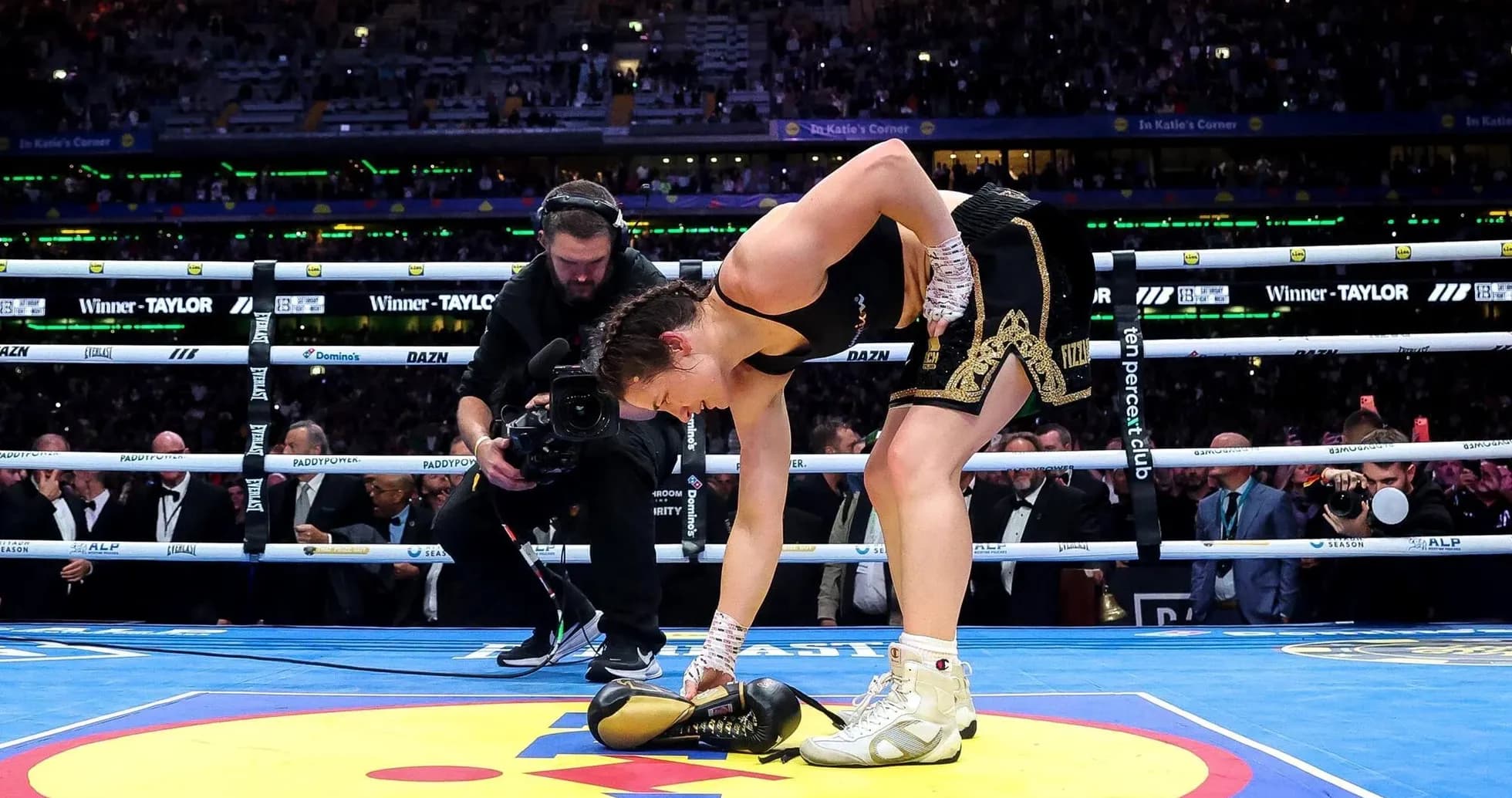 Boxer picking up gloves in the ring after victory