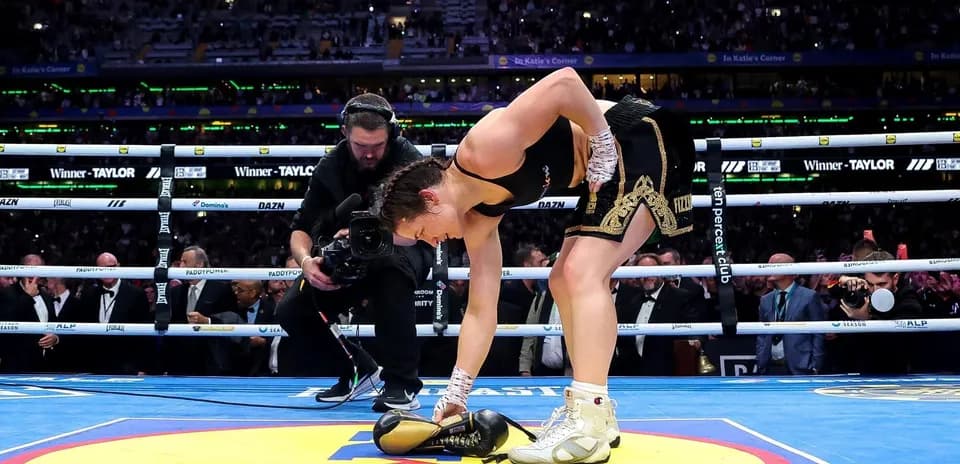 Boxer picking up gloves in the ring after victory