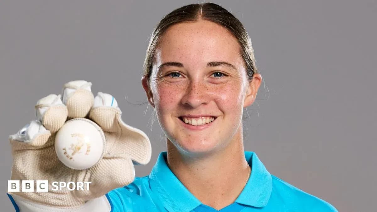 Cricketer holding a ball and smiling at camera