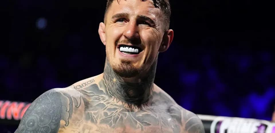 Boxer smiling in ring with tattoos visible