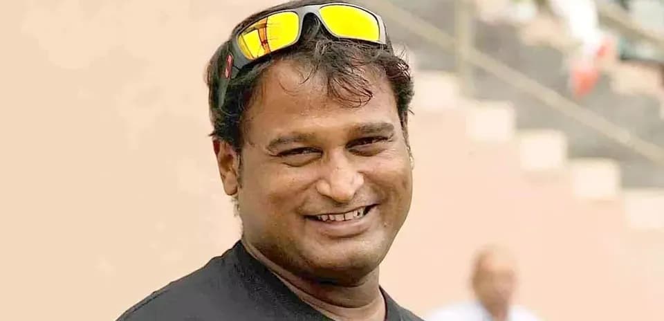 Smiling man wearing sunglasses at a sports venue